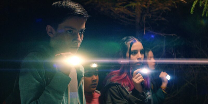 Die „Libellen“-Gruppe – Louis (Oliver Cunliffe), Glen (Krish Misra), Kaz (Maiya Silveston) und Meg (Katy Byrne, von links) – verfolgt Finn und seine Clique, die im Wald hinterm Zaun in einer verlassenen Hütte eine Party feiern wollen. – Bild: ZDF/​Zodiak Kids Studio UK Limited