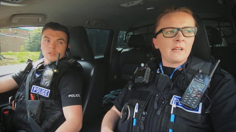 Polizeibeamte patrouillieren in ihrem Streifenwagen durch das Zentrum der Stadt. – Bild: Warner Bros. Discovery