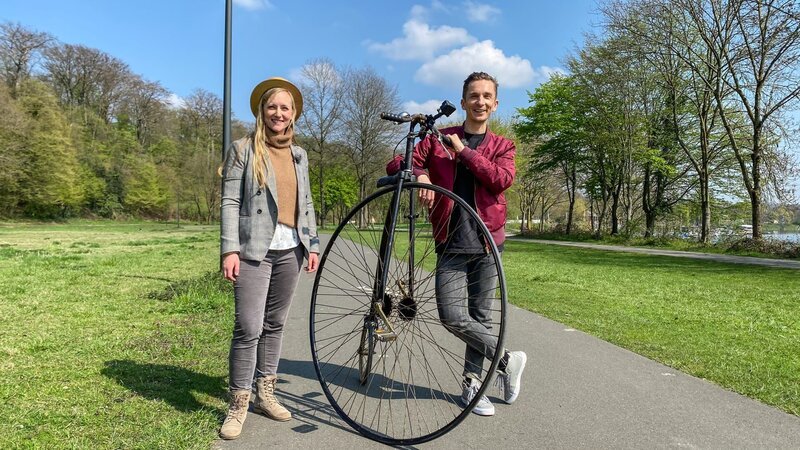 Fahrradfahren wie vor fast 200 Jahren? „PUR+“- Moderator Eric Mayer möchte wissen, wie es sich anfühlt, auf einem Hochrad unterwegs zu sein. Schafft er es überhaupt aufs Rad? Wie hält man dort oben das Gleichgewicht? Unterstützung erhält Eric Mayer durch Hochradlehrerin Pia Floren. – Bild: ZDF/​Sandra Palm