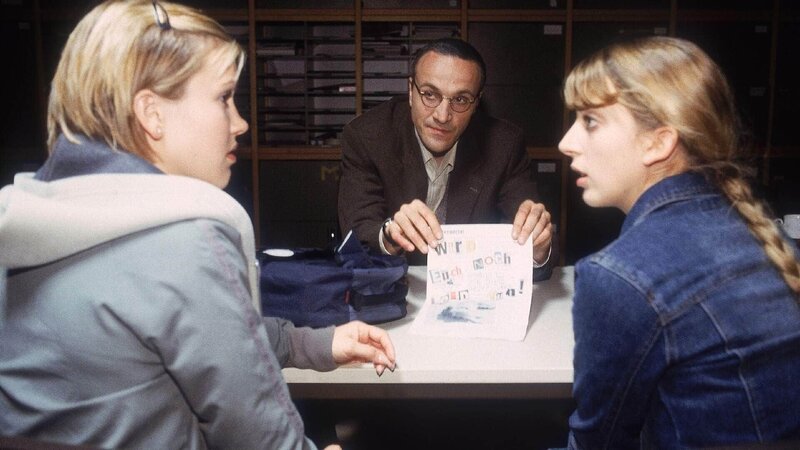 Schulleiter Kanus (Andreas Durban), selbst Opfer von Claudias Modekolumne, ist nicht sehr beeindruckt von dem Drohbrief, den Alex (Wolke Hegenbarth, li.) und Claudia (Nora Binder) bekommen haben. – Bild: RTL /​ Kai Schulz