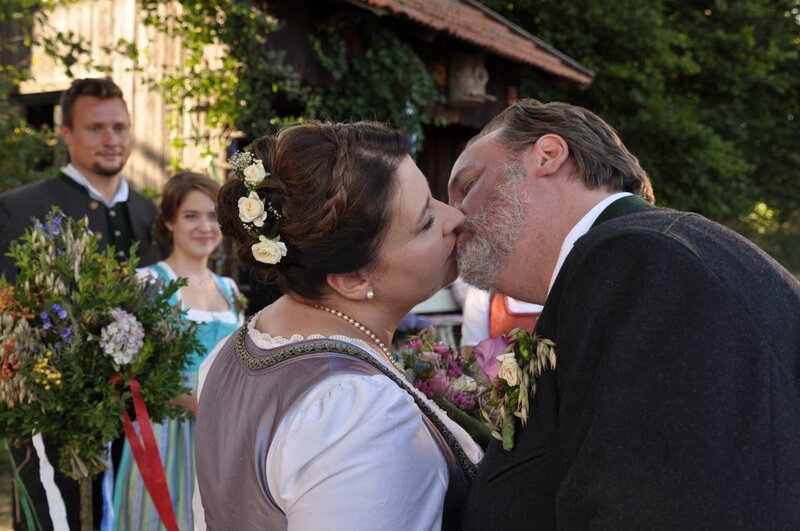 Mit einem Kuss besiegeln Moni und Benedikt ihre frisch geschlossene Ehe. Von links: Leopold Vogl (Maximilian Laprell), Katharina Benninger (Carina Dengler), Monika Vogl (Christine Reimer) und Benedikt Stadlbauer (Andreas Geiss). – Bild: Jo Bischoff /​ BR