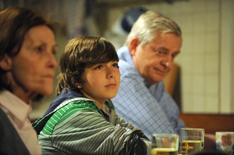 Joseph, Felix und seine Oma warten gespannt auf die Entscheidung von Frau Breinbauer. Von links: Frau Kramer (Astrid Polak), Felix Kramer (Shayan Hartmann) und Joseph Brunner (Wilhelm Manske). – Bild: BR/​Marco Orlando Pichler