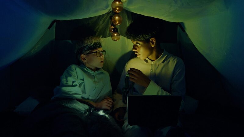 William (Caleb Kebreab, rechts) will Mattis (Leon Mosand-Christensen, links) überreden, einen Horrorfilm im Zelt zu schauen. – Bild: WDR/​Annicken Aasheim/​Alvilde Naterstad