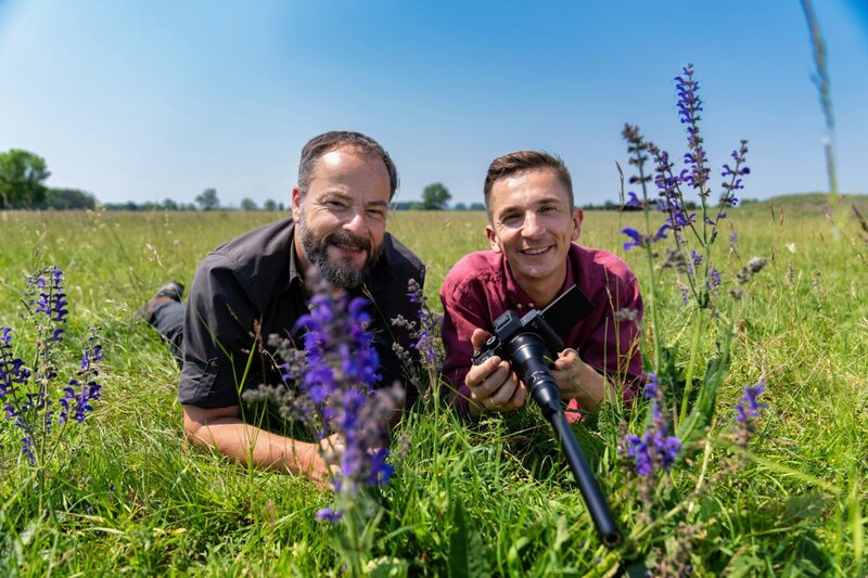 Naturfilmer Jan Haft (l.) nd Eric Mayer (r.) liegen in einer Wiese. Eric Mayer hält eine Kamera mit Schnorcheloptik in Händen. – Bild: ZDF/​Florian Lippke