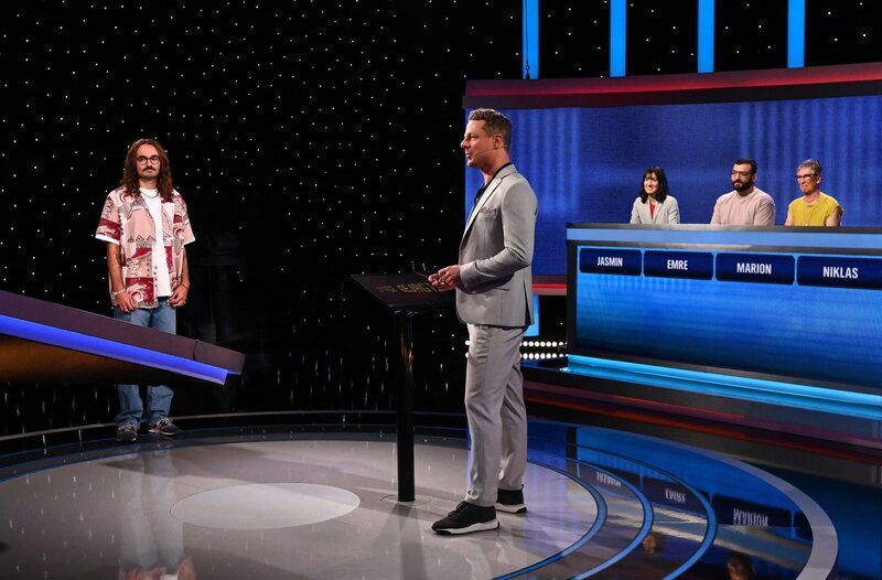 Moderator Alexander Bommes (M.) mit den Kandidat:innen: Niklas Kohlmann (l.), Jasmin S.(3.v.r.), Emre Burunsuz (2.v.r.) und Marion Koschel (r.). – Bild: ARD/​Uwe Ernst