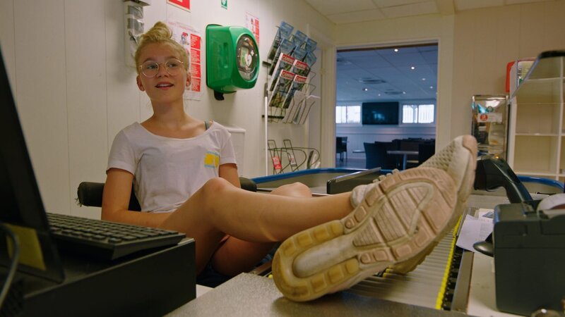 Andrine (Selma Adeline Opedal) arbeitet gern im Supermarkt des Campingplatzes. – Bild: WDR/​Annicken Aasheim/​Alvilde Naterstad