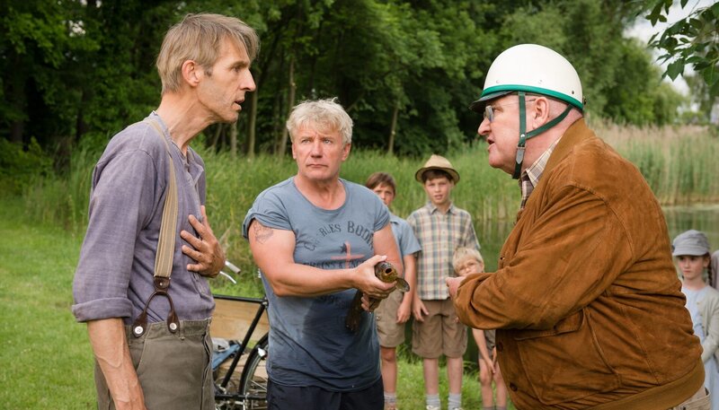 Polizeihauptmeister Krause (Horst Krause, re.) empört sich darüber, dass sein Freund Schlunzke (Andreas Schmidt, li.) und dessen neuer Freund Albert (Jörg Schüttauf) im Dorfteich Fische fangen. – Bild: rbb /​ Stephan Rabold