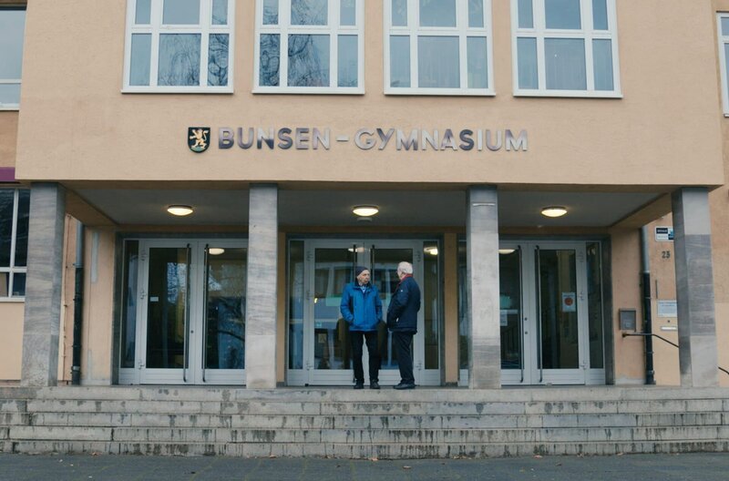 Klaus Staeck (re.) mit seinem Schulfreund Siegfried Schmohl (li.) vor deren ehemaligen Schule in Heidelberg: Nach der Flucht aus der DDR mussten sie dort ihr Westabitur ablegen. – Bild: Lona media/​Philip Koepsell