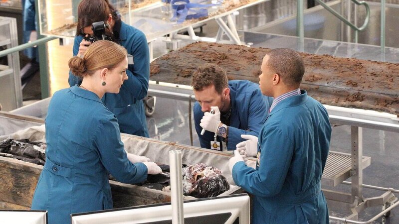 (v.l.) Angela (Michaela Conlin), Brennan (Emily Deschanel), Hodgins (TJ Thyne) und Clark (Eugene Byrd) untersuchen die exhumierte Leiche eines Mannes, der lt. Totenschein an Leukämie gestorben sein soll. Doch das Team vermutet einen Mord. – Bild: TVNOW /​ FOX