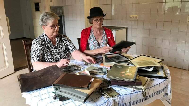 Annedore Knaack und Ina Schwarz schauen sich Fotos an und erinnern sich an die über 100-jährige Geschichte des Elternhauses. Ihre Urgroßeltern haben es gebaut, nun soll es verkauft werden. – Bild: MDR/​Heike Dickebohm