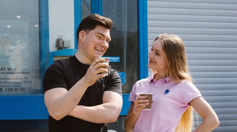 Christina und Ali vor der Werkstatt im Gespräch. – Bild: BR/​Bianca Taube