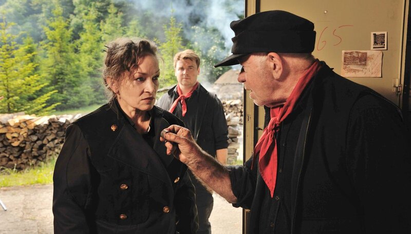 Karl Brenner (Uli Krohm, l.) zeigt seiner Frau Angela (Angelika Bartsch, l.) den Halstuchring ihres ermordeten Sohnes, den er im Schrank ihres jüngeren Sohnes Till (Tobias Nath, im HG) gefunden hat. – Bild: ARD/​Hardy Spitz