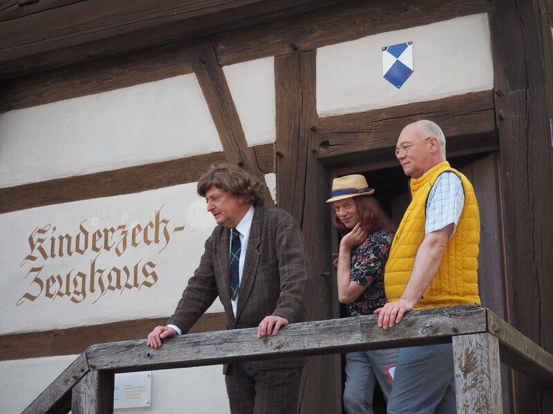 Ortsbesichtigung: Stadtverwalter Dieter Dachs (Volker Heißmann, links) und sein Mitarbeiter (Oliver Severin, Mitte), zeigen Dr. Konrad Landzenberg aus dem Bundeskanzleramt (Martin Rassau, rechts) die Vorzüge des beschaulichen Dinkelsbühl. – Bild: Amelie Völker / BR Ortsbesichtigung: Stadtverwalter Dieter Dachs (Volker Heißmann, links) und sein Mitarbeiter (Oliver Severin, Mitte), zeigen Dr. Konrad Landzenberg aus dem Bundeskanzleramt (Martin Rassau, rechts) die Vorzüge des beschaulichen Dinkelsbühl. – Bild: Amelie Völker / BR