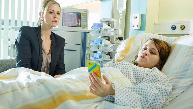 Karin Noske (Jessica Ginkel, l.) sitzt besorgt an Lucca’s (Janina Fautz) Krankenbett, als Luccas Mutter anruft und Karin mit ihrer Reaktion entsetzt. – Bild: TVNOW /​ Frank Dicks /​ Sony Pictures FFP
