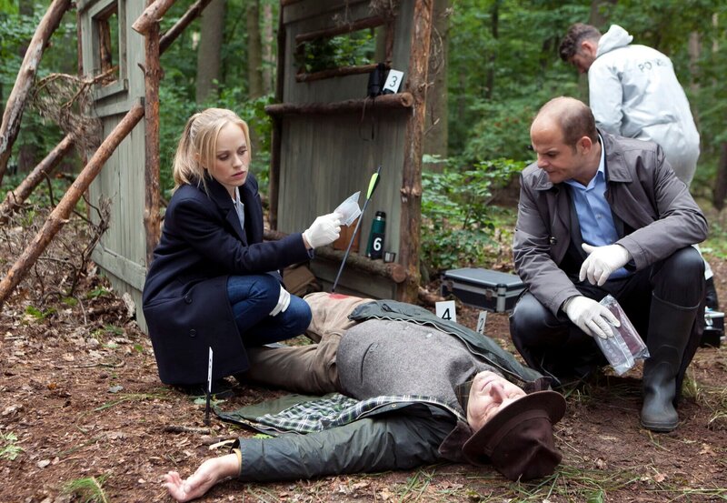 Der Jäger Jan Frenzel (Komparse) wird am frühen Morgen im Berliner Stadtwald durch den Bolzen einer Armbrust tödlich getroffen. Julia Klug (Friederike Kempter, l.) und Johannes Sonntag (Matthias Klimsa, r. mit Kompase) begutachten die Spuren am Tatort. – Bild: NDR/​ARD/​Daniela Incoronato