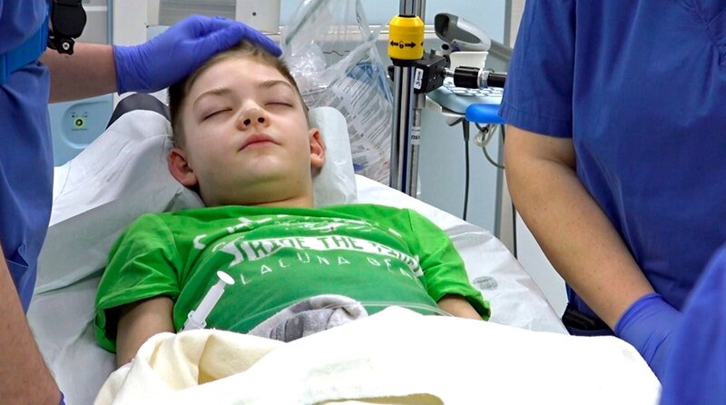 Die Ärzte behandeln Julian im Schockraum. Johannes Horter streichelt seinen Kopf. – Bild: SWR