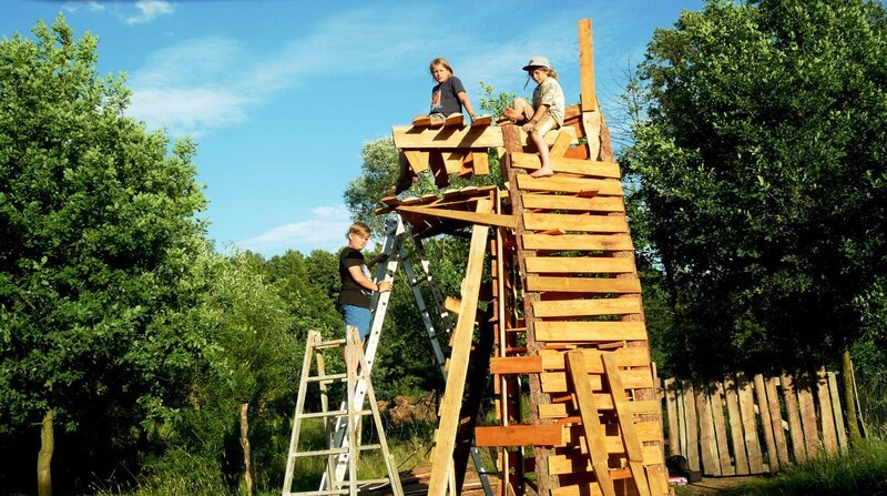 Janko, Paul und Juli bauen einen Drachenturm aus Holz für das Sommersonnen-Wendefest. – Bild: rbb/​Klaus TĂĽmmler