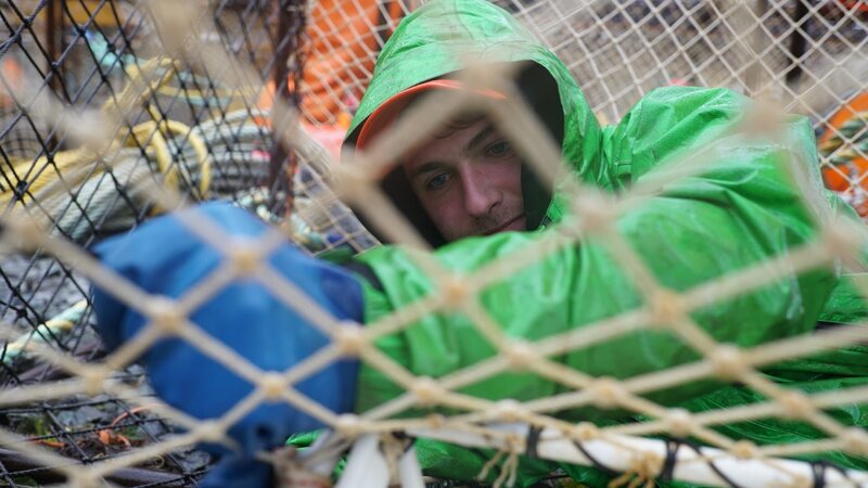 On F/​V Summer Bay, Deckhand Spencer Moore has the ever important task of prepping pots, ensuring that no crab can escape through holes. – Bild: Discovery Channel /​ Discovery Communications