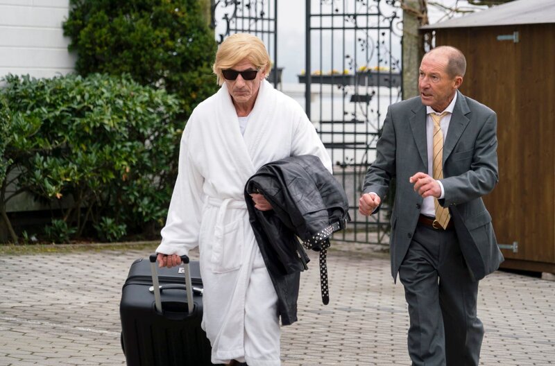 Klinikchef Konrad Weiss (Michael Lesch, r.) laufen bereits die ersten Gäste weg (Komparse, l.). – Bild: ARD/​TMG/​Arvid Uhlig