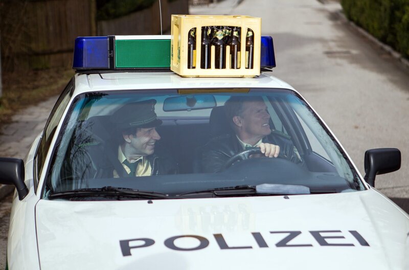 Hubert (Christian Tramitz, rechts) und Staller (Helmfried von Lüttichau) haben ihr neues „Accessoire“ auf dem Dach des Polizeiautos noch nicht bemerkt. – Bild: ARD/​TMG/​Chris Hirschhäuser