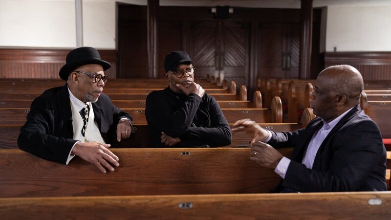 Samuel L. Jackson (M.) spricht mit den Musikern Clark White (l.) und Paul Kwami (r.) über ein altes Sklavenlied, das auf den Baumwollfeldern gesungen wurde. – Bild: ZDF