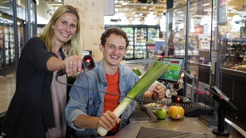 Kassiererin Svenja zeigt Julian wie eine Supermarktkasse funktioniert und startet mit ihm ein Kassier-Battle. – Bild: BR /​megaherz gmbh/​Lena Stolz