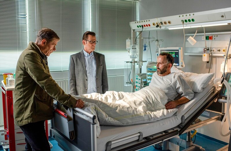 Als Uwe Trimborn (Sami Loris, r.) aus dem Koma erwacht ist, erhoffen sich Finn (Sven Martinek, l.) und Lars (Ingo Naujoks, M.) wichtige Hinweise von ihm. – Bild: ORF/​ONE GATE/​ARD/​Thorsten Jander