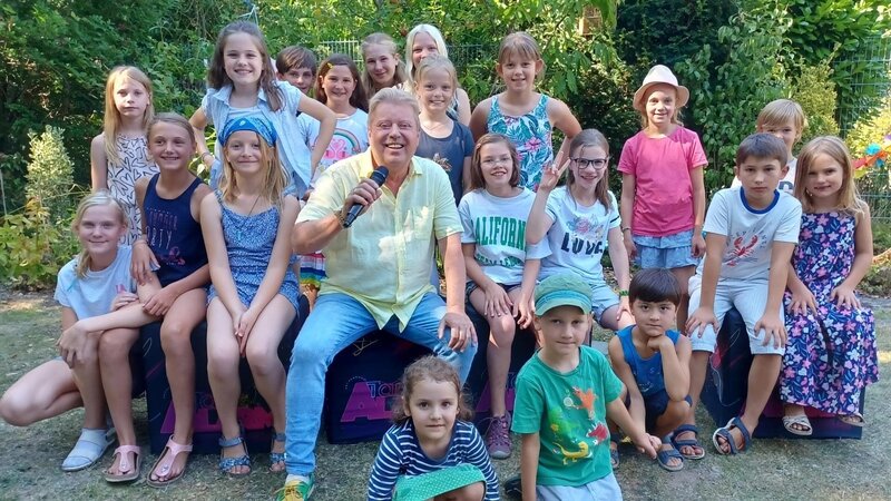 Volker Rosin feiert mit Alina, Kilian und ihren Freunden eine super Gartenparty. – Bild: KiKA/​Anne Reichenbach