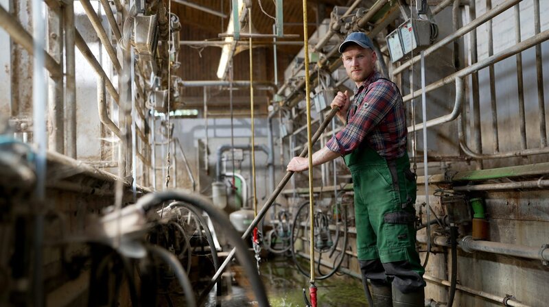 Sven Ole Johansson steht plötzlich in einem leeren Melkstand. – Bild: NDR/​Reinhard Bettauer