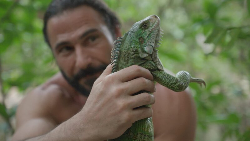 Hazen holding a green iguana. – Bild: National Geographic/​Alex Holden
