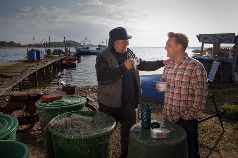 Fiete (Dietmar Bär, l.) trinkt mit Piet (Axel Stein, r.) ein Becher Tee. Fiete wollte Piet unbedingt etwas sagen, aber es fällt ihm so schwer, das er wieder schweigt. – Bild: ZDF