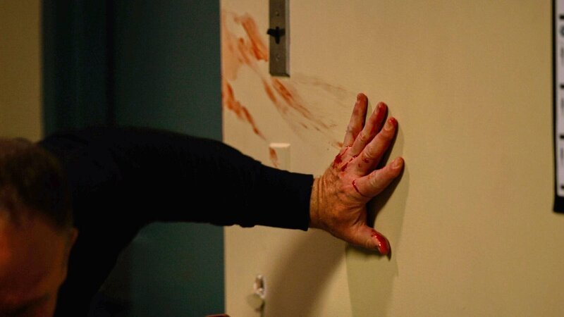 Ein Mann klammert sich mit einer blutigen Hand an die Wand – Bild: Crime + Investigation /​ fairpoint