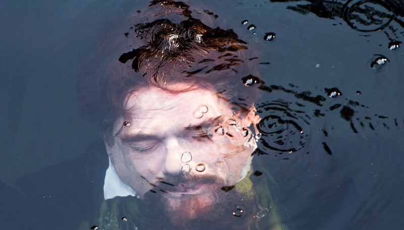 Bayerisches Fernsehen DIE REICHEN LEICHEN. EIN STARNBERGKRIMI, am Samstag (18.10.14) um 20:15 Uhr. Starnberg, höchste Millionärsdichte Bayerns, eine Idylle mit Reißzähnen. Hierhin verschlägt es Polizeimeisteranwärterin Ariane aus Dortmund, die hiesige Mentalität könnte ihr nicht fremder sein, weshalb Inspektionsleiter Lu sie umso entschiedener unter seine Fittiche nimmt. Ihre ersten Fälle sind typisch und seltsam zugleich: Der Kini wird tot im See gefunden – noch mal. Ein Wiedergänger des Märchenkönigs Ludwig II., nicht zu identifizieren. Noch während Lu, Ariane und Kollege Timo von der Kripo im Dunkeln der mystischen Vergangenheit tappen, ereignet sich ein weiteres Verbrechen: Die Sisi wird entführt. Der Kini (Martin Feifel) wird tot im See aufgefunden. – Bild: BR/​Julia von Vietinghoff