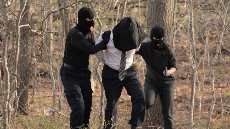 Eco-terrorists lead a hooded Sidney through the woods at gun point – Bild: Discovery Communications