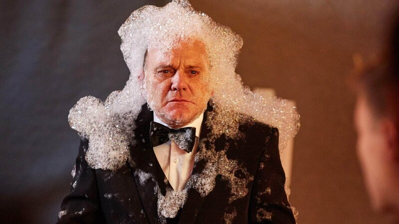 Direktor Rose (Uli Gebauer) muss beim Auftritt der „Four Strings“ ein nicht ganz freiwilliges Schaumbad nehmen. – Bild: TVNOW /​ Frank Dicks /​ Sony Pictures FFP