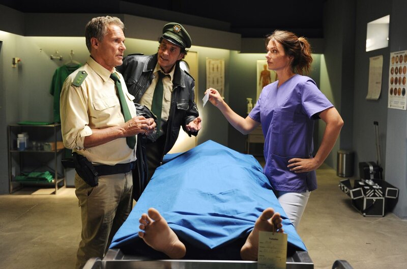 Auf die Hilfe von Dr. Caroline Fuchs (Susu Padotzke, r.) können sich Hubert (Christian Tramitz, l.) und Staller (Helmfried von Lüttichau, M.) verlassen. Der Tote wurde offensichtlich vergiftet. – Bild: ARD/​TMG/​Chris Hirschhäuser