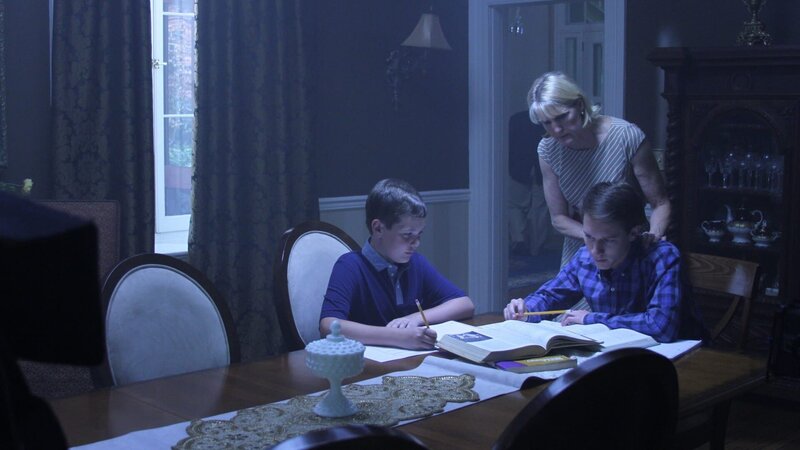Recre- Neil and Stewart at table doing homework as mom consoles them. – Bild: Discovery