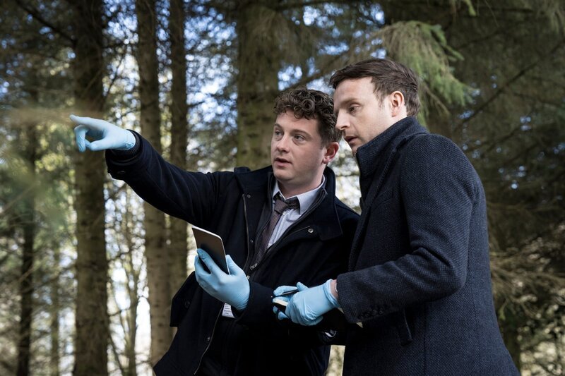 DI Archie Dent (Josh Bolt, l.) macht Harper (Andrew Gower, r.) mit den Lokalitäten des neuen Falls vertraut. – Bild: Steffan Hill /​ ZDF und Steffan Hill
