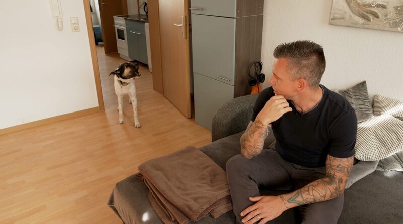 Hündin Diva reagiert verunsichert auf Fremde, auch auf Trainer Steve Kaye (r), als er Julia und Diva zum ersten Mal besucht. Sie bleibt auf Abstand und bellt. – Bild: WDR/​Meworks GmbH