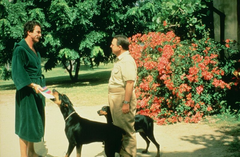 Jonathan Higgins (John Hillerman, r.) teilt Thomas Magnum (Tom Selleck, l.) mit, dass seine Cousine Sally nach Hawaii kommt, um in eine der ältesten Familien der Insel einzuheiraten. – Bild: Universal City Studios LLLP