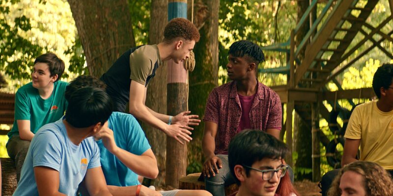 In der realen Welt informiert Elliot (D’Nico Greaves, M.l.) Finn (Jordan Adene, M.r. ) während einer Versammlung im Camp darüber, dass Louis, Kaz, Bea und Glen verschwunden sind. Er hat es mit eigenen Augen gesehen und weiß, dass Meg noch irgendwo im Camp sein muss. – Bild: ZDF/​Zodiak Kids Studio UK Limited