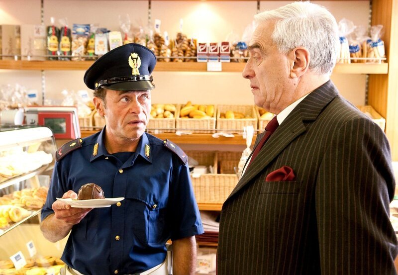 Vice-Questore Patta (Michael Degen, r.) überführt Alvise (Dietmar Mössmer), der eine politisch nicht korrekte Bezeichnung für eine Süßspeise benutzte. – Bild: port.hu