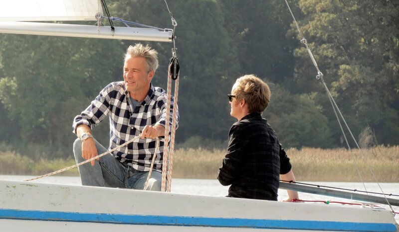 Hannes Jaenicke (li.) lädt Pierre zu einem Segelbootausflug auf dem Ammersee ein. – Bild: SWR/​Encanto
