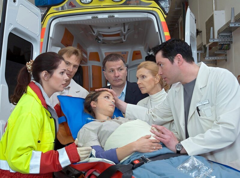 Als Arzu mit Dr. Elena Eichhorn und Dr. Roland Heilmann in der Sachsenklinik ankommt, werden sie von Dr. Martin Stein und Oberschwester Ingrid erwartet. Als Philipp angerannt kommt, beruhigt Arzu ihn und legt seine Hand auf ihren Bauch – das Baby bewegt sich. – Von links: Dr. Elena Eichhorn (Cheryl Shepard); Dr. Martin Stein (Bernhard Bettermann); Arzu Ritter (Arzu Bazman); Dr. Roland Heilmann (Thomas Rühmann); Oberschwester Ingrid (Jutta Kammann); Dr. Philipp Brentano (Thomas Koch). – Bild: MDR/​Krajewsky