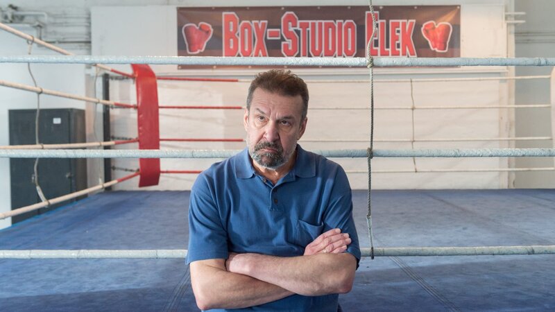 Am Abend zuvor hat Trainer Balász Elek (Jurij Rosstalnyj) Ronny intensiv auf einen Kampf vorbereitet. Er ist damit scheinbar der Letzte, der ihn lebendig gesehen hat. Was ist zwischen den beiden vorgefallen? Hat es Streit gegeben? – Bild: Marc Meyerbroeke /​ ZDF