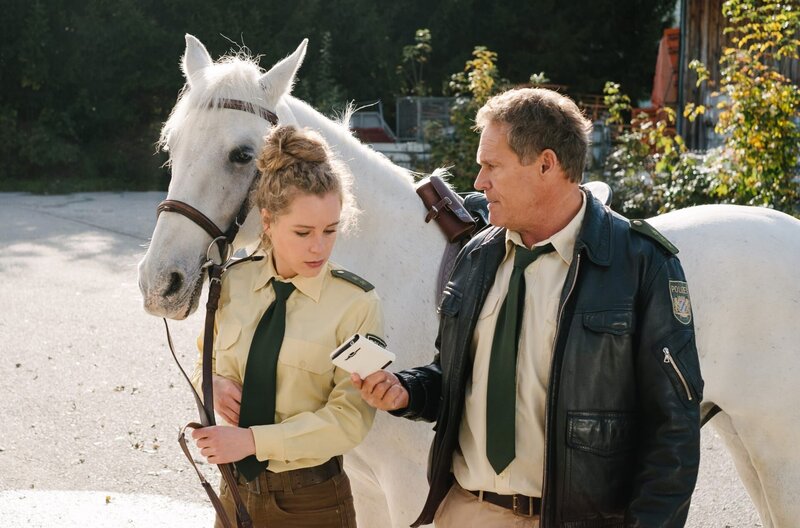 Das herrenlose Pferd mit dem Handy in der Satteltasche gibt Hubert (Christian Tramitz, r.) und Lena (Klara Deutschmann, l.) Rätsel auf. – Bild: ARD/​TMG/​Emanuel Klempa