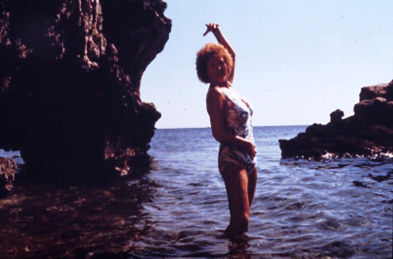 Noch genießt die Hausmeisterin Martha Haslbeck (Veronika Fitz) ihren Besuch bei Costa im griechischen Kalamata in vollen Zügen. Doch bald merkt sie, dass nichts mehr so ist, wie es in München war … – Bild: BR/​Tatiana Film GmbH & Co. Audio KG