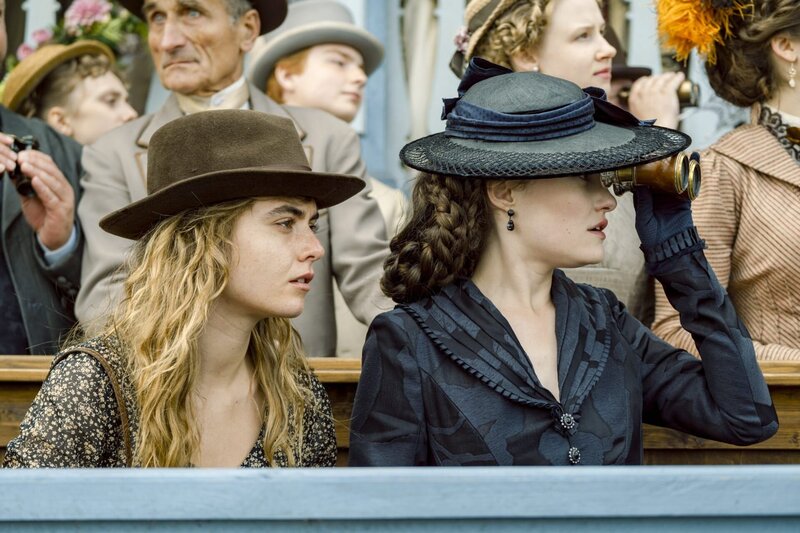 Sisi (Dominique Devenport) engagiert ihre Halbschwester und ehemalige Stallmeisterin Linda (Eli Riccardi, l.) als Reittrainerin. Gemeinsam besuchen sie ein Pferderennen von Sisis Konkurrenten Georg Basselet von La Rosée. – Bild: ORF/​Beta Film/​RTL/​Story House Pictures/​Armands Virbulis