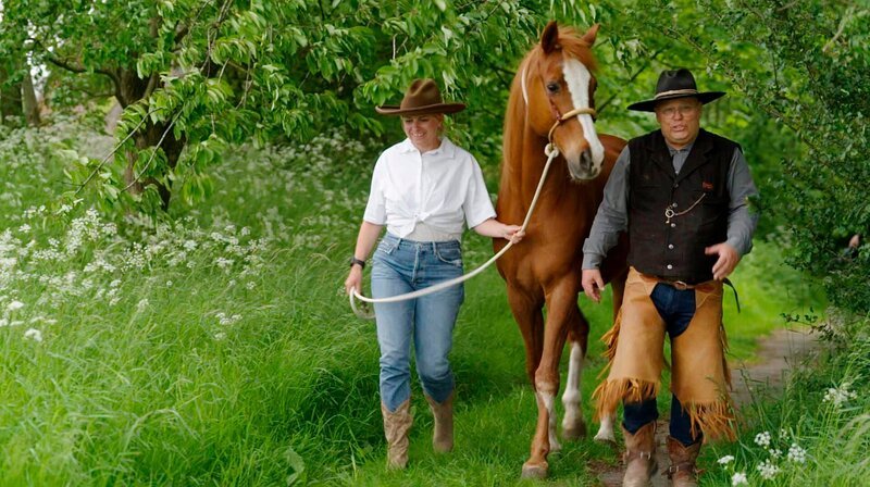 Wanderreiten im Westernreitzentrum Lippe-Hof. Westernreiter Erich (r) zeigt Sabine Heinrich seinen Hof, erzählt ihr von seiner Wildwest-Sehnsucht und lädt sie zum Wanderreiten ein durchs Weserbergland. – Bild: WDR/​klarlogo