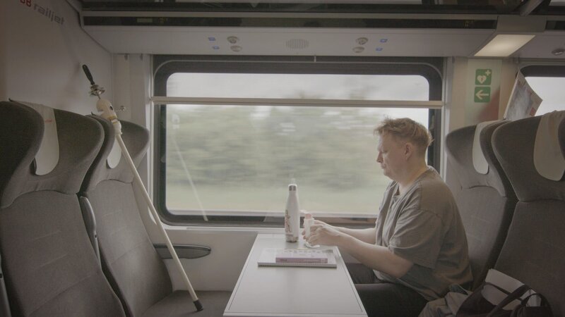 Patrick im Zug mit „Klapperzahn“, dem Instrument von Hans Tschiritsch. – Bild: ORF/​Feuer&Flamme Film/​Florian Gebauer